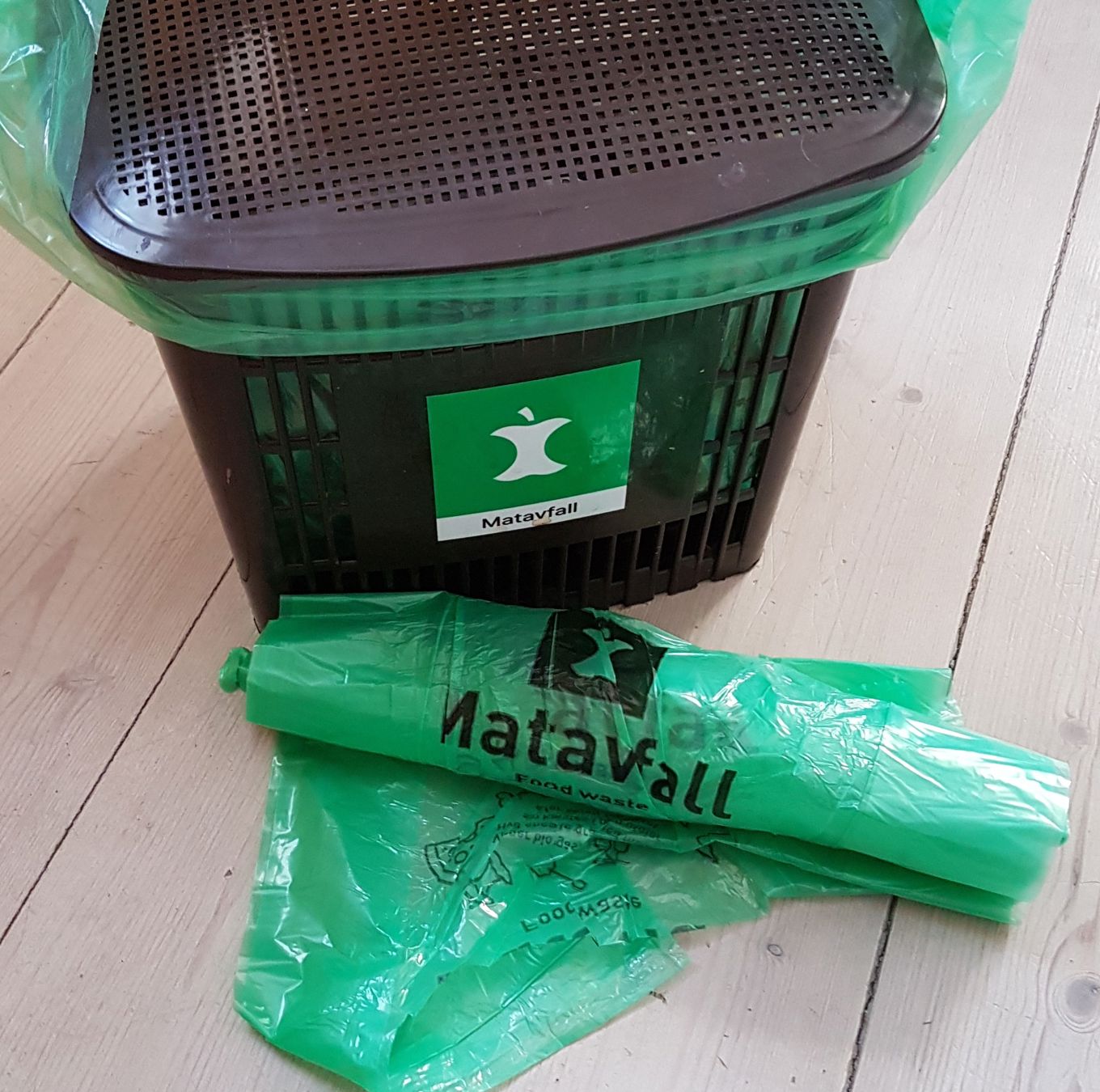 En grønn søppelbøtte med grønt lokk og grønn plastpose En grønn søppelbøtte med grønt lokk og grønn plastpose